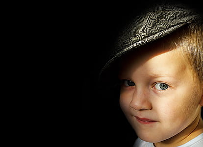 boy wears black hat inside dark room thumbnail