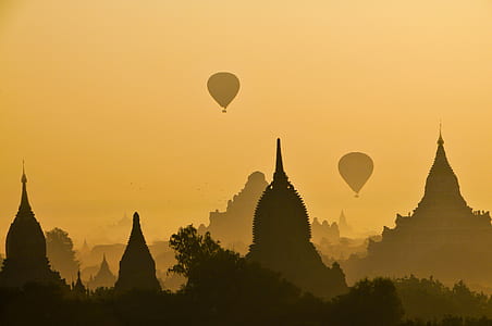 silhouette photography of two hot air balloons on four towers thumbnail