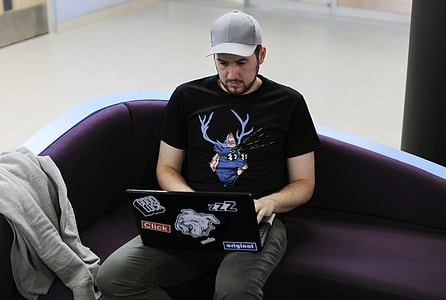 person in black shirt sitting in purple sofa holding black laptop thumbnail