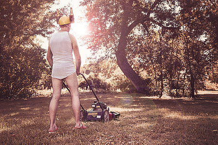 person using push mower wearing yellow helmet thumbnail