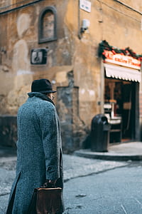 person wearing gray coat walking in village thumbnail
