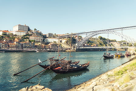 two brown boats under suspension bridge during daytime thumbnail