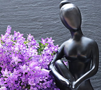 gray metal woman figurine beside purple flowers thumbnail