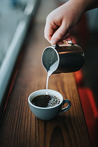 person holding gray stainless steep teapot of coffee pouring to white ceramic cup thumbnail