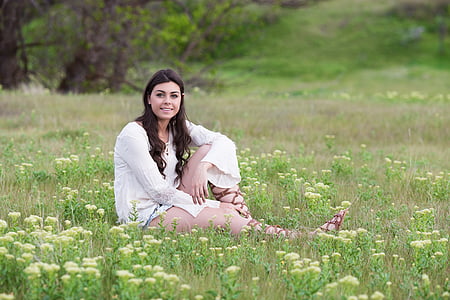 woman in white top sitting on grass during daytime thumbnail