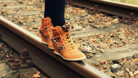 person wearing brown leather wedge sneakers on train rail thumbnail