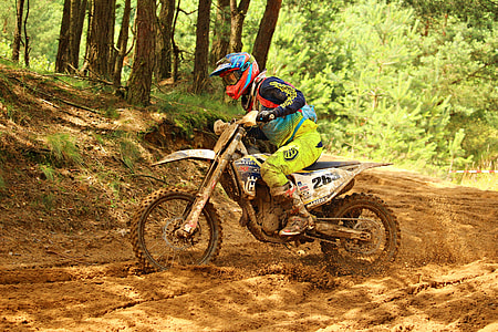man riding white motocross dirt bike in the middle of mud roadway thumbnail