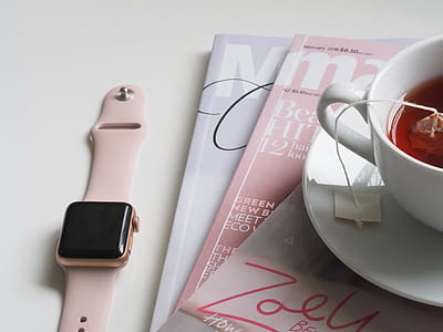 rose gold aluminum case Apple Watch with pink Sport Band beside magazines thumbnail