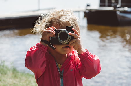 girl holding film camera near river thumbnail