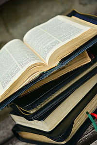 pile of black and blue bibles on brown and white wooden board photo thumbnail