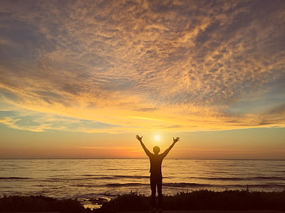 silhouette of man standing on seashore during sunset thumbnail