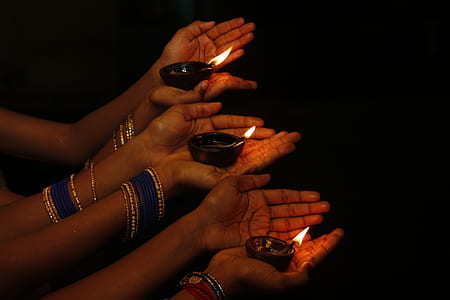 three lighted candles on person's hands thumbnail