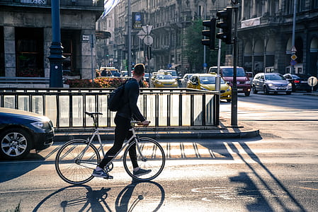 man holding bike walking on road thumbnail