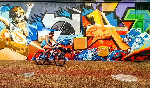 woman riding bike beside graffiti thumbnail