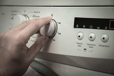 person turning knob of washing machine thumbnail
