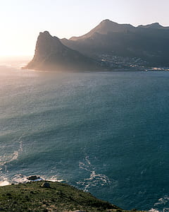 body of water beside mountain during daytime thumbnail