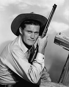 grayscale photo of man holding rifle thumbnail