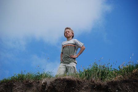 boy standing on edge of grass field thumbnail