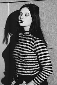 woman stands near wall while smokes thumbnail