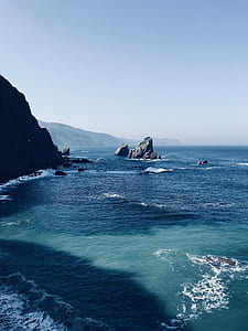 rock formation in body of water during cloudy sky thumbnail