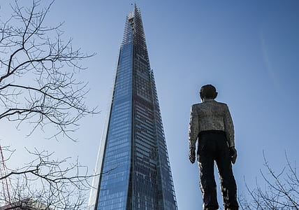 Man Standing in Front of a Sunrise Building Under Blue Sky thumbnail