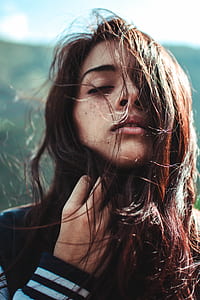 close-up photography of woman in black and white jacket holding her hair during daytime thumbnail