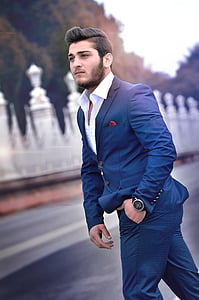 man wearing blue suit jacket and dress pants standing near road thumbnail