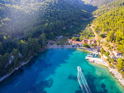 ship of body of water surrounded by mountains and buildings thumbnail