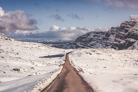 snow covered field and mountains under blue sky thumbnail