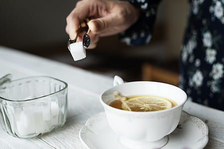 person pouring sugar cubes on tea thumbnail