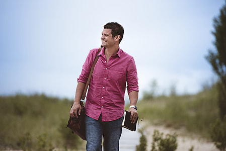 man in purple dresshirt and brown leather messenger bag and blue denim pants thumbnail