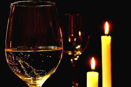 two wine glasses beside two taper candles thumbnail