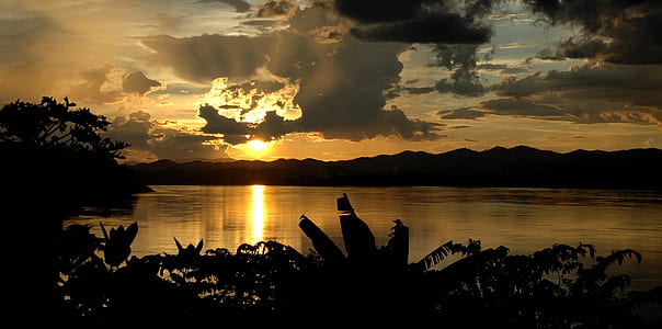 silhouette photography of mountain and body of water thumbnail