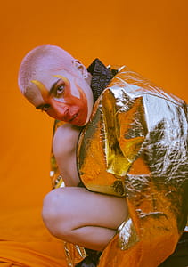 Woman Wearing Silver Zip-up Jacket Kneeling on Orange Textile thumbnail