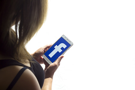 woman holding smartphone with Facebook logo thumbnail