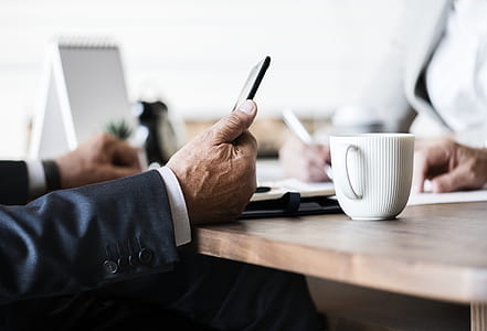 person leaning on table beside white cup on tabletop thumbnail