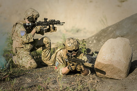 two person's wearing brown military clothes holding two black assault rifles thumbnail