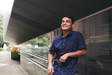 Man in Blue Button-up Shirt Standing Beside Glass Wall thumbnail