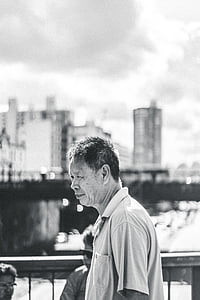 greyscale photo of man near wooden rail thumbnail