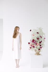 Woman in White Spaghetti Strap Midi Dress Standing Beside Table With Flowers thumbnail