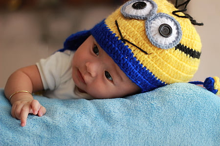 baby boy laying on blue cloth wearing Minion chullo hat thumbnail