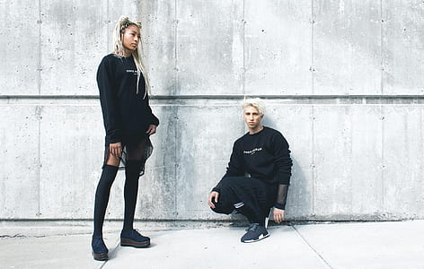 man sitting in front of wall near standing woman thumbnail