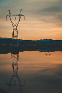 gray metal power transmission reflector on calm body of water during golden hour thumbnail