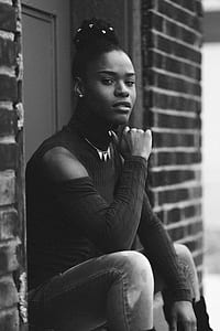 grayscale photography of woman sitting on stairs near door closed thumbnail