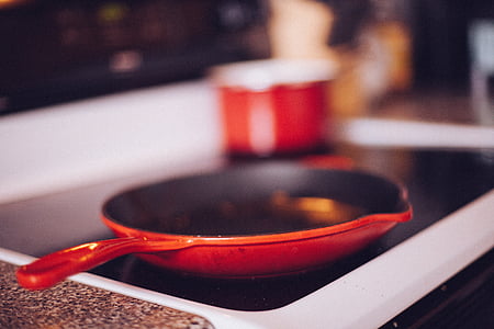 red frying pan on black stove thumbnail