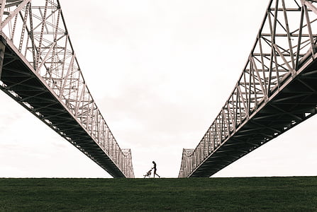 silhouette photography of person pushing stroller under bridge thumbnail