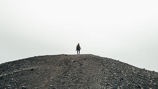 A hiker carrying a camera standing on a gravel hill thumbnail
