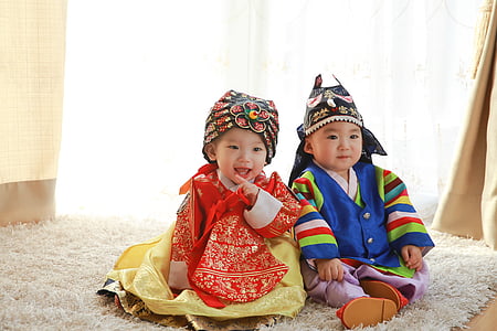 two children in traditional clothes sits on white fleece rug thumbnail