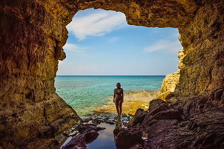 woman standing near cave during daytime thumbnail