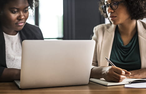 Two Women Sitting on Chair in Front of Laptop on Table Inside Room thumbnail